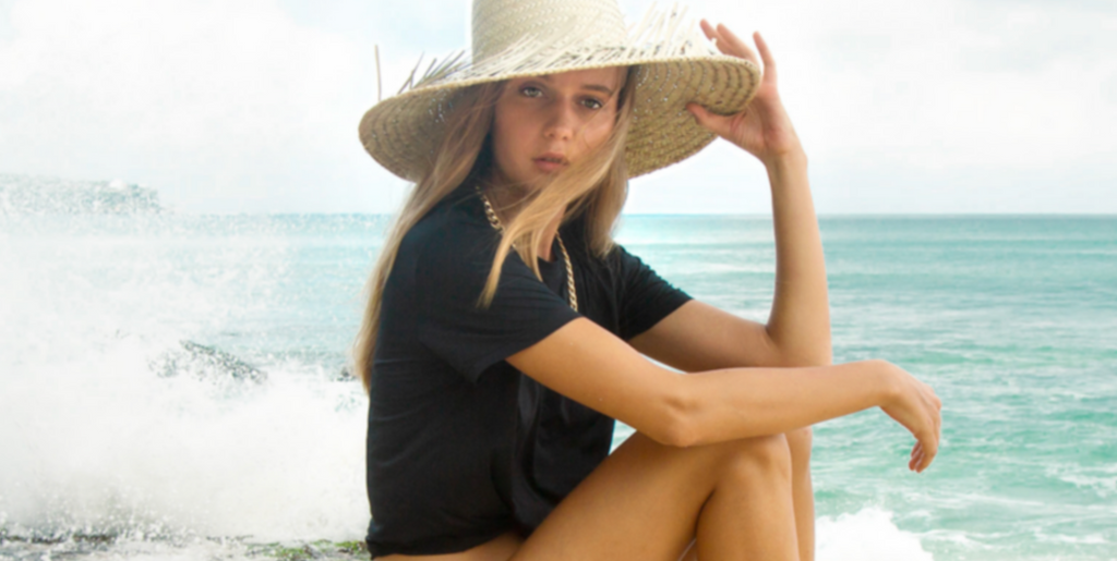 Girl on beach in straw hat wearing Outfyt 