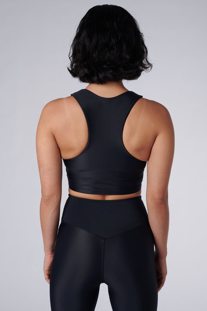 Award-winning black crop top with a flattering cut, high neckline for coverage, and in-built sports bra. Medium impact support, perfect for day wear, back view