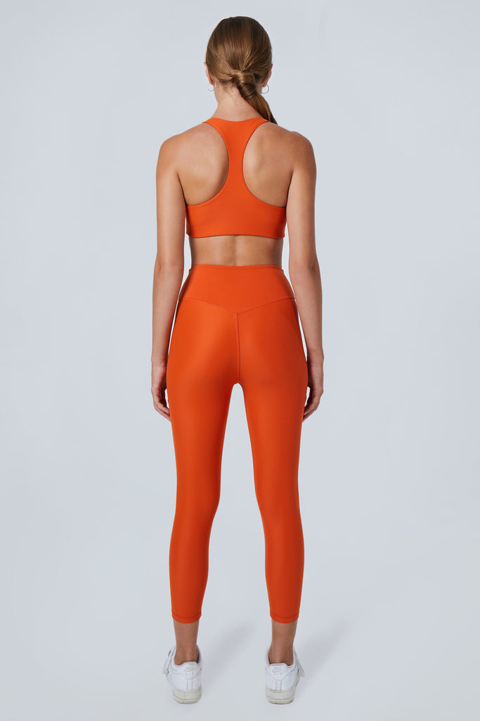 Super soft orange high-waisted 7/8 leggings without a front seam for all-day comfort. Perfect for non abrasive sports and everyday wear, back view