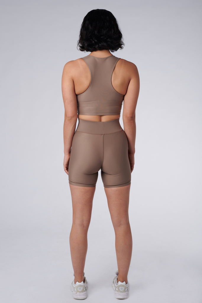 High-waisted beige bicycle shorts with a secure, compressive fit. No front seam and flattering wide waist band, back view