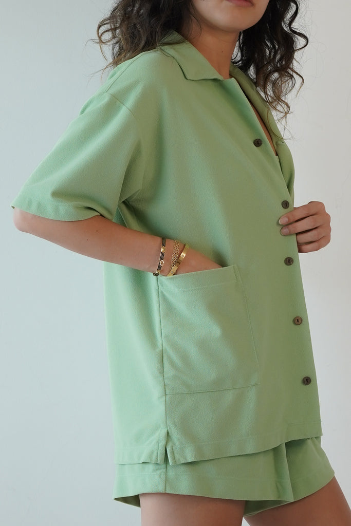 Mint green shirt in eco-friendly soft technical terry. Features coconut buttons, big pockets, and a lightweight feel, close up
