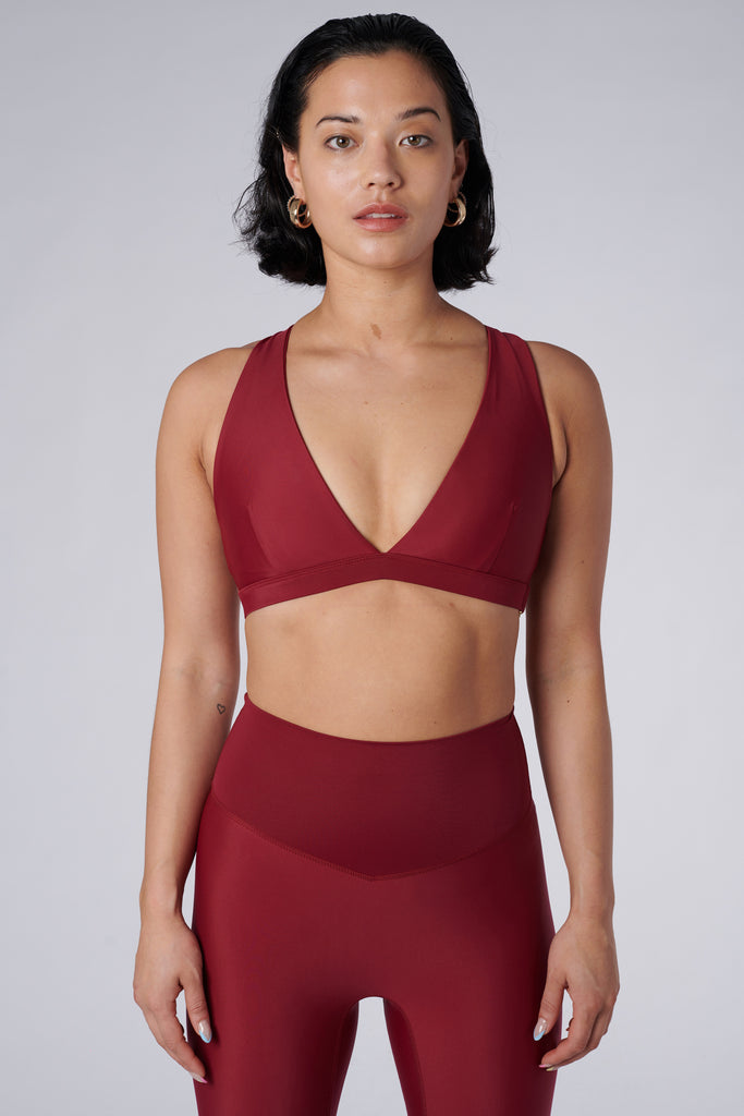 Dark red, medium to high impact support with removable padding, strong elastic cross back straps, and adjustable gold-hook closure, front view